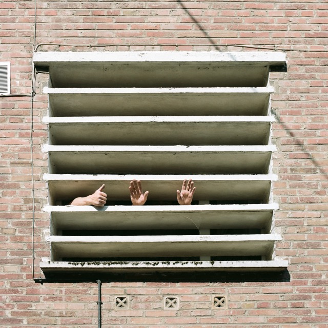 Des mains à travers passées à travers des lames de béton sur une façade